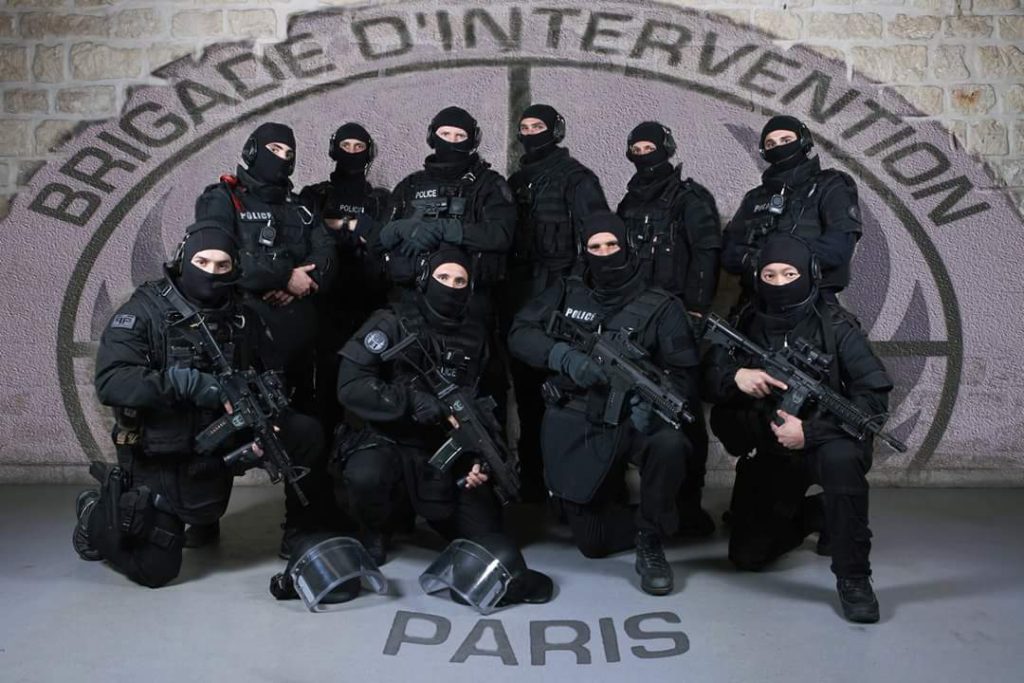 Les opérateurs de la Brigade d'Intervention devant l'écusson de l'unité à Paris